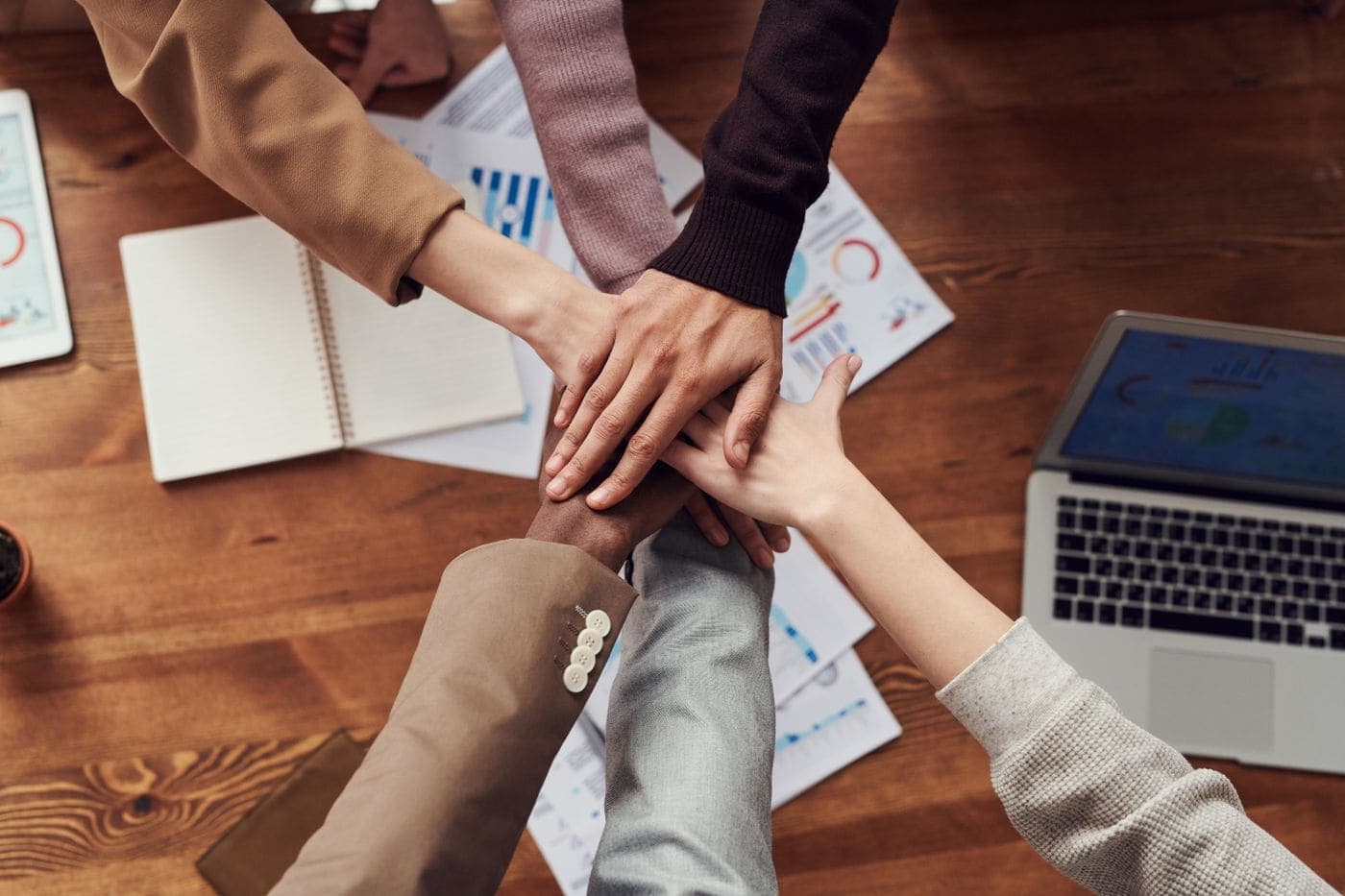 Diverse professionals collaborating with hands stacked in unity